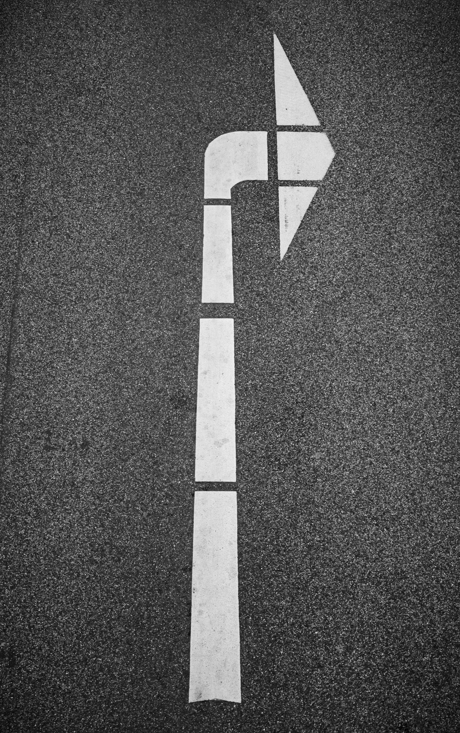 Freshly painted white turn arrow on dark asphalt
